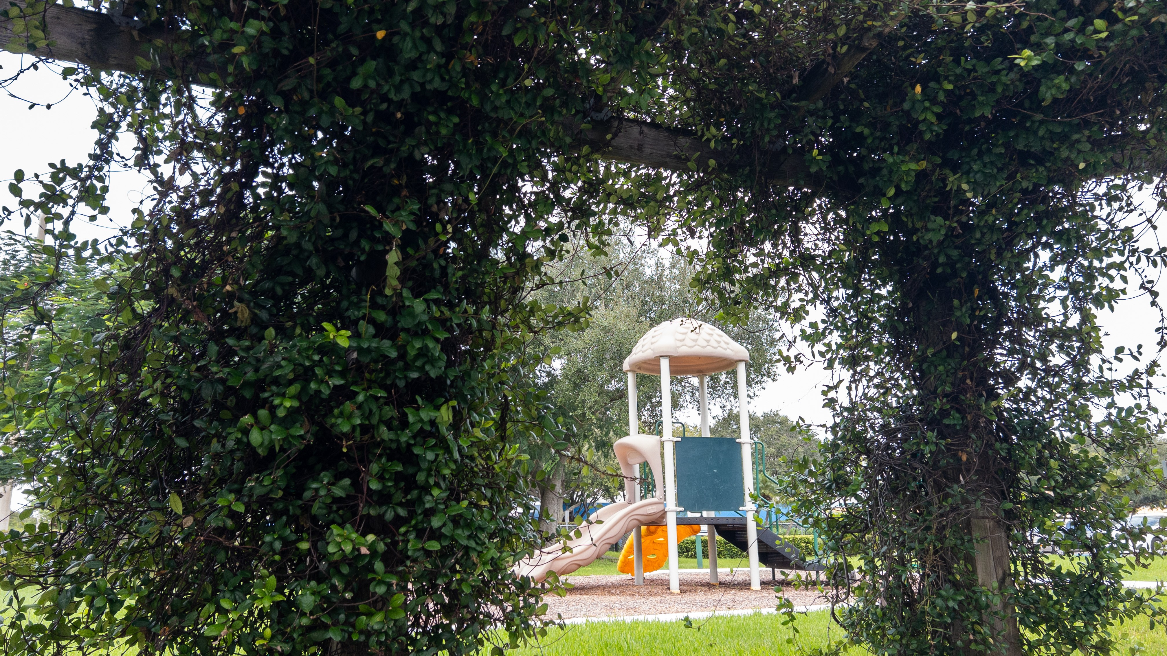 A playground with a green slide and a white tower.